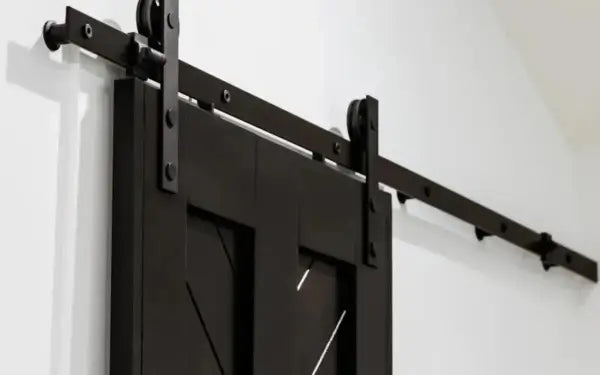 Black sliding barn door with metal track on a white wall