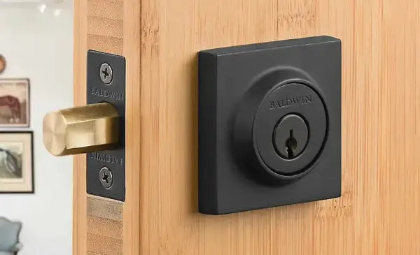Black door handle and lock on a wooden door with a blurred indoor background