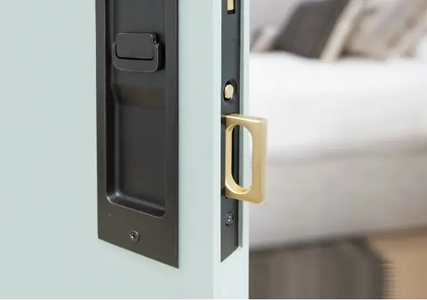 Close-up of a door handle and lock mechanism with a blurred bedroom background