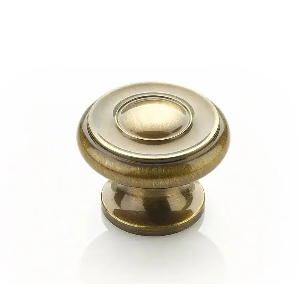 The Schaub Traditional Stepped Round Cabinet Knob in Antique Brass finish.