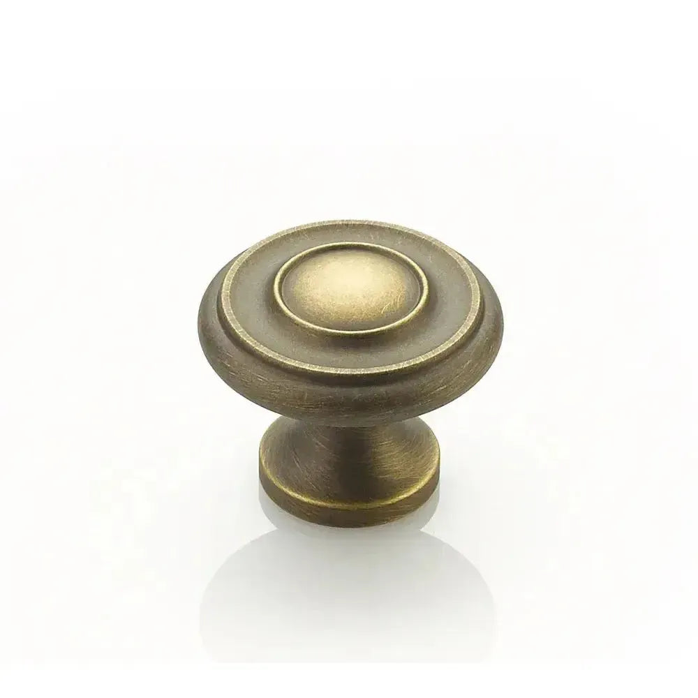 The Schaub Traditional Stepped Round Cabinet Knob in Antique Light Brass finish.