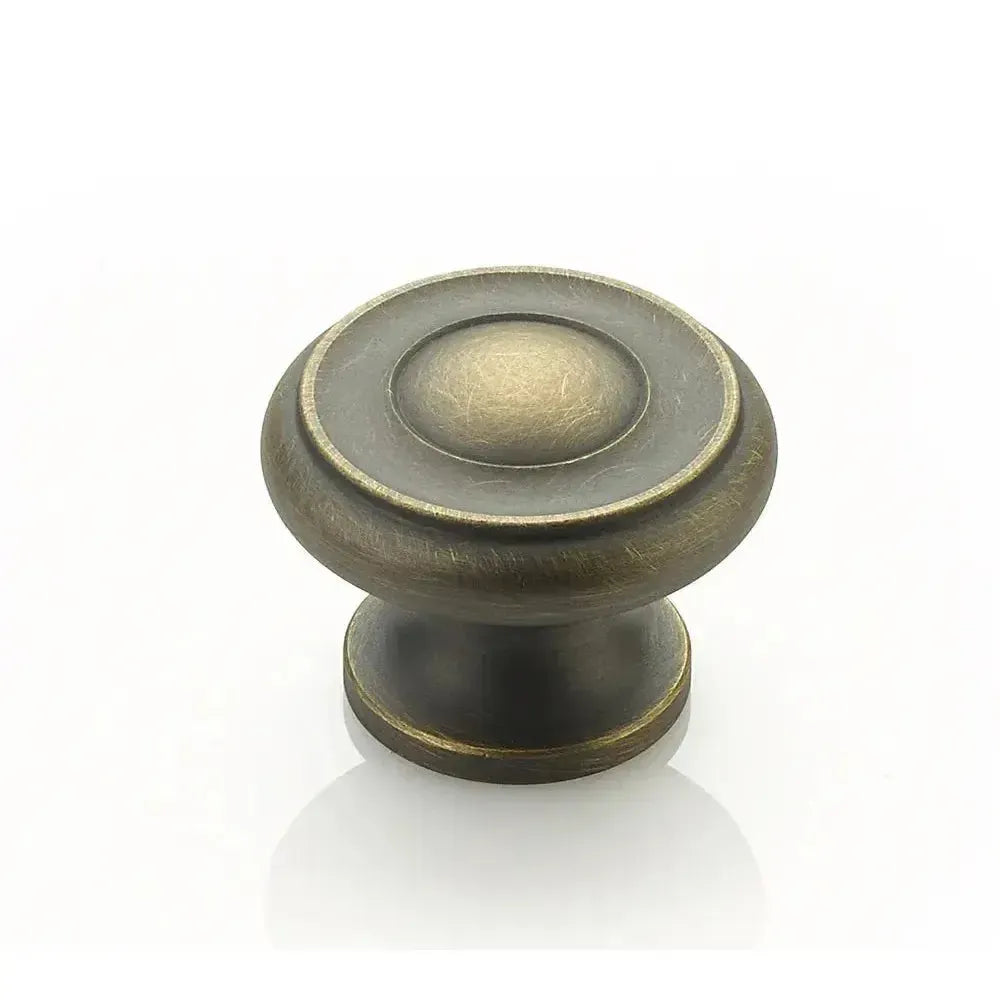 The Schaub Traditional Stepped Round Cabinet Knob in Antique Light Brass finish.