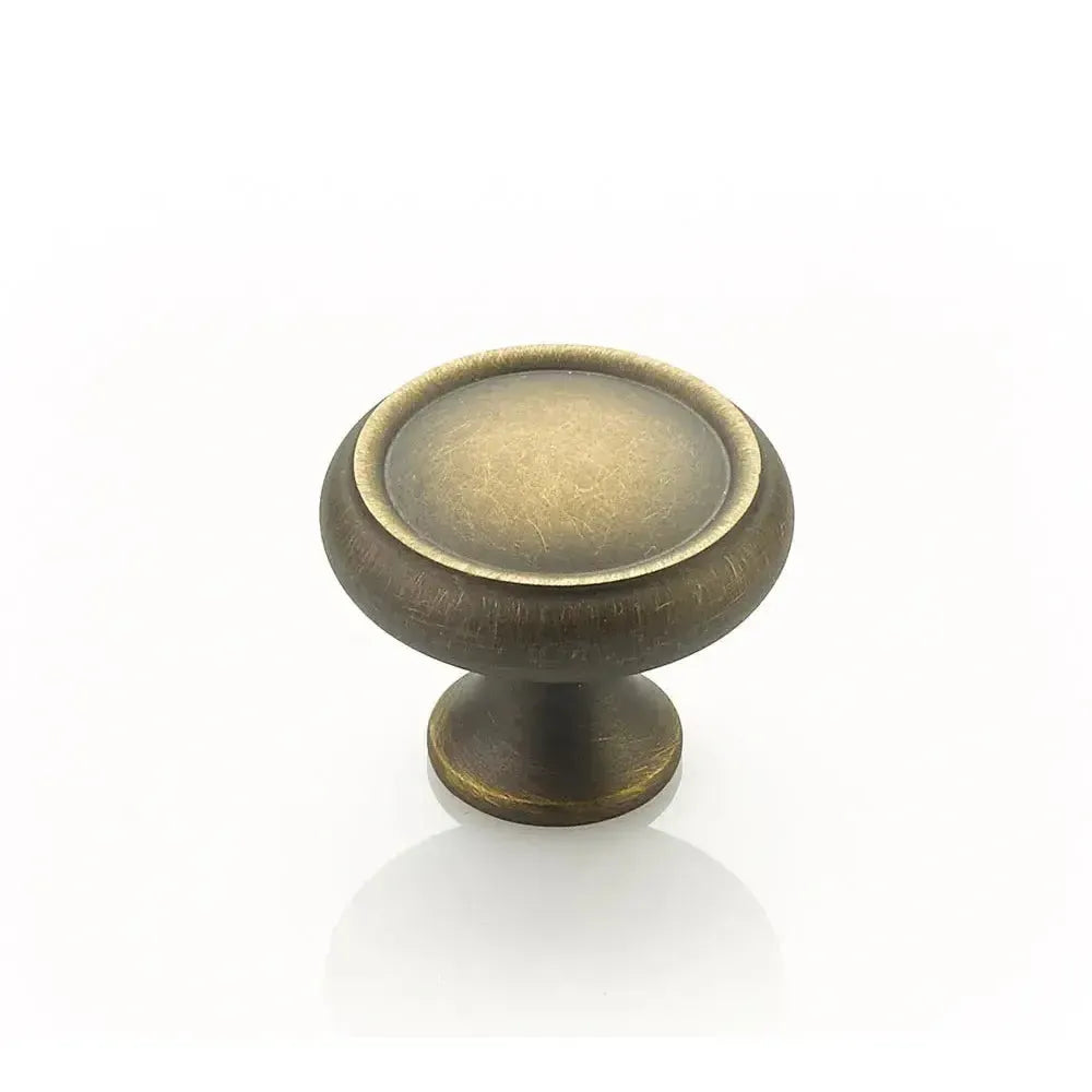 The Schaub Country Rimmed Round Cabinet Knob in Antique Light Brass finish.