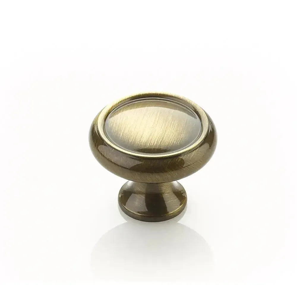 The Schaub Country Rimmed Round Cabinet Knob in Antique Brass finish.