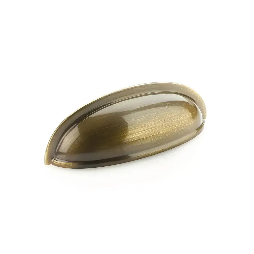 The Schaub Traditional Cup Cabinet Pull in Antique Brass finish.