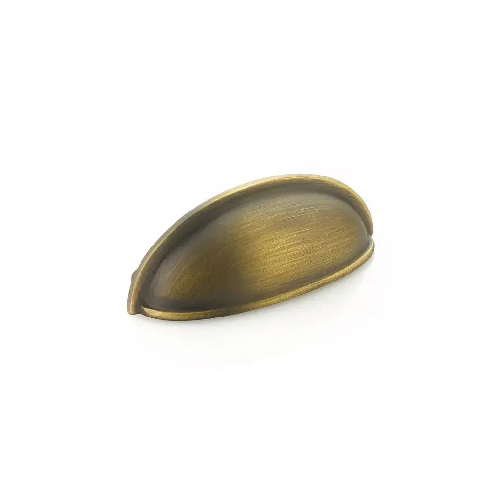 The Schaub Traditional Cup Cabinet Pull in Antique Light Brass finish.