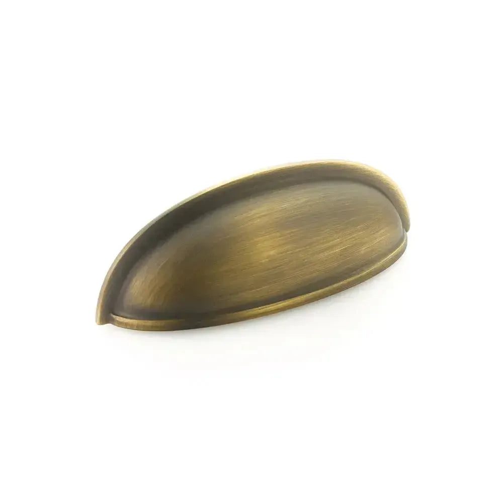 The Schaub Traditional Cup Cabinet Pull in Antique Light Brass finish.