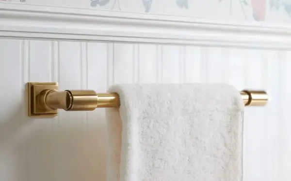Gold towel rack with a white towel on a white wall
